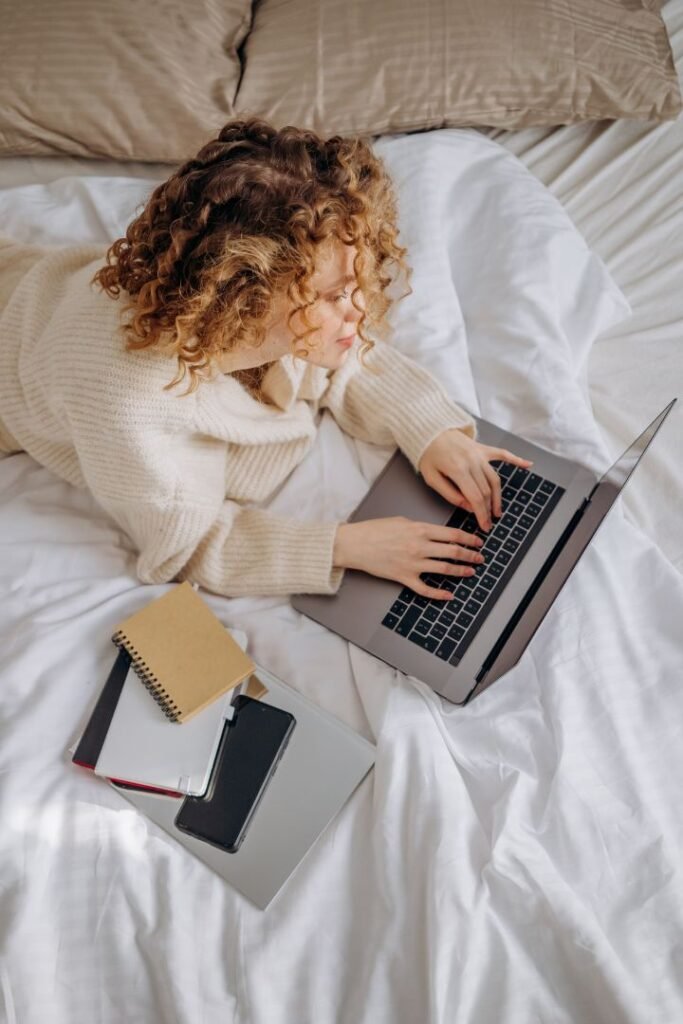 women working on laptop from bed