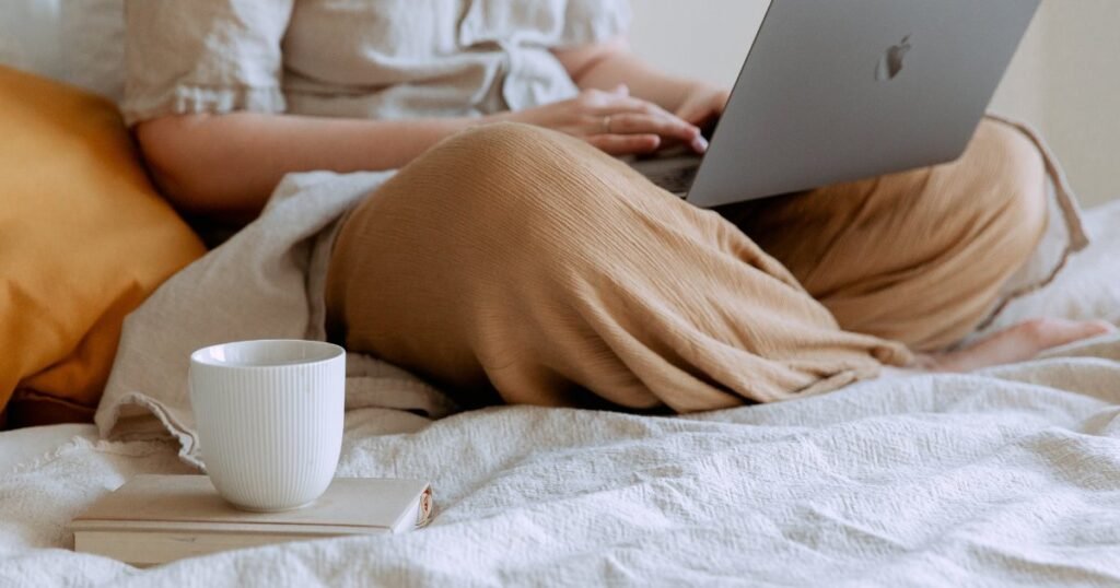woman blogging on bed with laptop and coffee
